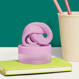 Pink focus putty on its container, sitting on a lime-green notebook next to a cup with pencils.