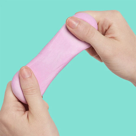 Two hands pulling and stretching soft-pink focus putty against a bright turquoise background.