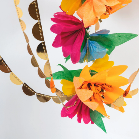Detailed view of colorful paper blossoms and shiny gold foil scallop strands on a chandelier decoration.