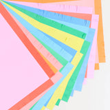 Close-up view of vibrant pastel paper placemats with fringed edges fanned out in a arc.