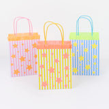 Three colorful, striped gift bags with star patterns and fringe trim against a white background.