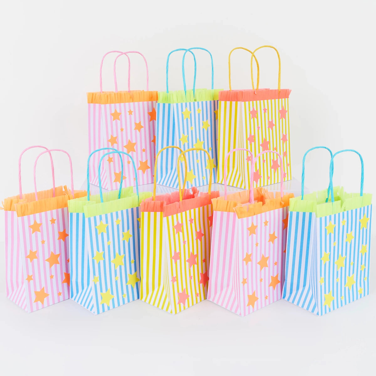 Row of colorful striped party bags with star patterns and fringe trim on a white background.