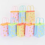 Row of colorful striped party bags with star patterns and fringe trim on a white background.