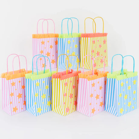 Row of colorful striped party bags with star patterns and fringe trim on a white background.