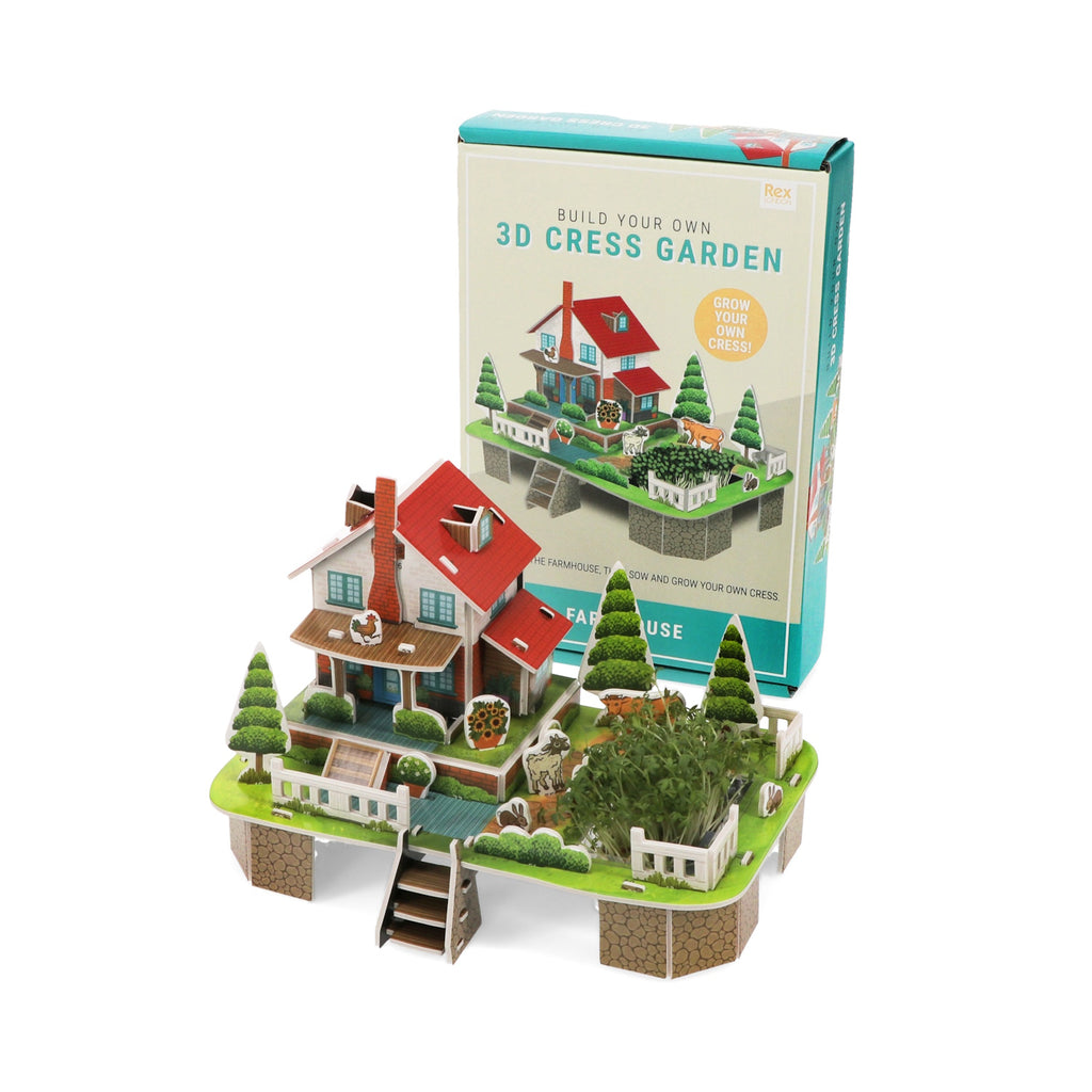 A colorful 3D model of a farmhouse and garden kit with cress plants, surrounded by trees and fences, next to its packaging.