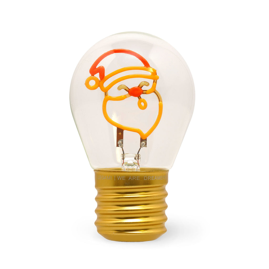 A transparent light bulb displays a glowing filament shaped like a Santa face with a red hat. The bulb’s base is golden, evoking a festive holiday theme.
