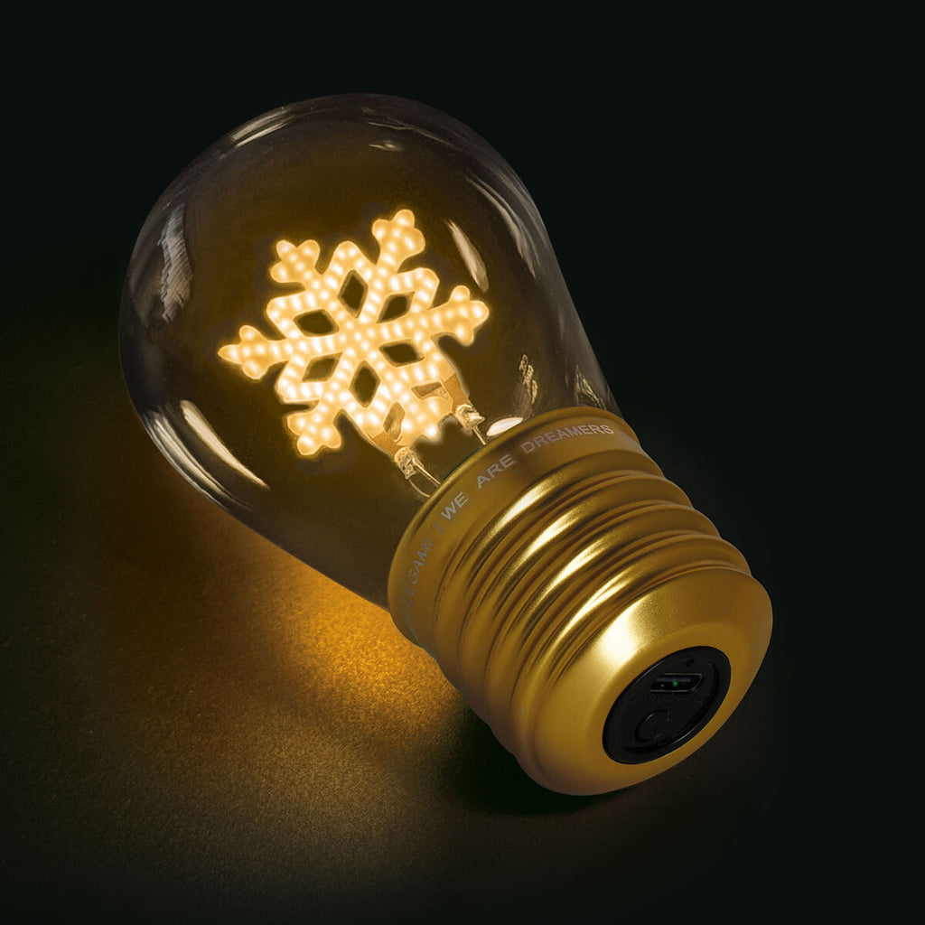 A glowing light bulb with a snowflake-shaped filament and a golden base, set against a dark background, exuding a warm and festive ambiance.