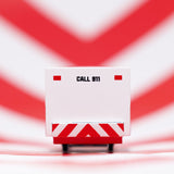 Rear view of a Candylab wooden ambulance toy car with "CALL 911" text, against a red and white chevron background.