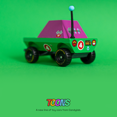 Rear view of Candylab Toons Dune-D adventure truck, a green and purple wooden toy car with a blue antenna and racing decals.