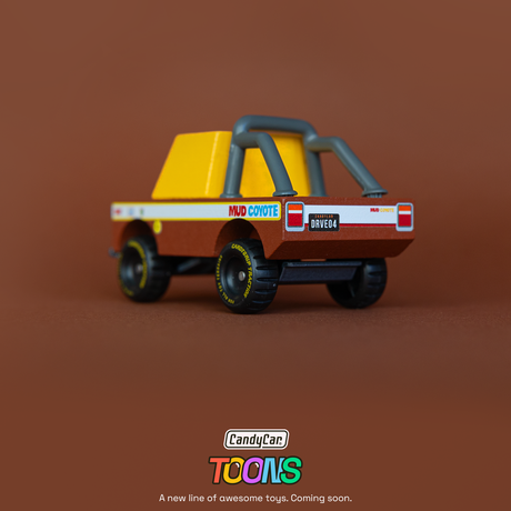 Rear view of a Candylab CandyCar Toons Mud Coyote wooden toy truck with yellow cab, roll bar, and chunky off-road tires.