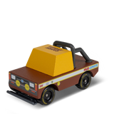 Wooden toy truck "Mud Coyote" by Candylab, featuring a brown body, yellow cab, and black off-road roll bar and tires.