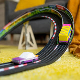 Colorful wooden toy van and purple car racing on a banked track in a living room; Candycar Speed Vandal by Candylab.