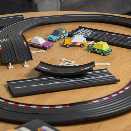 Four colorful Candylab wooden toy cars on a wooden table with a Waytoplay flexible rubber racing track and bone connectors.