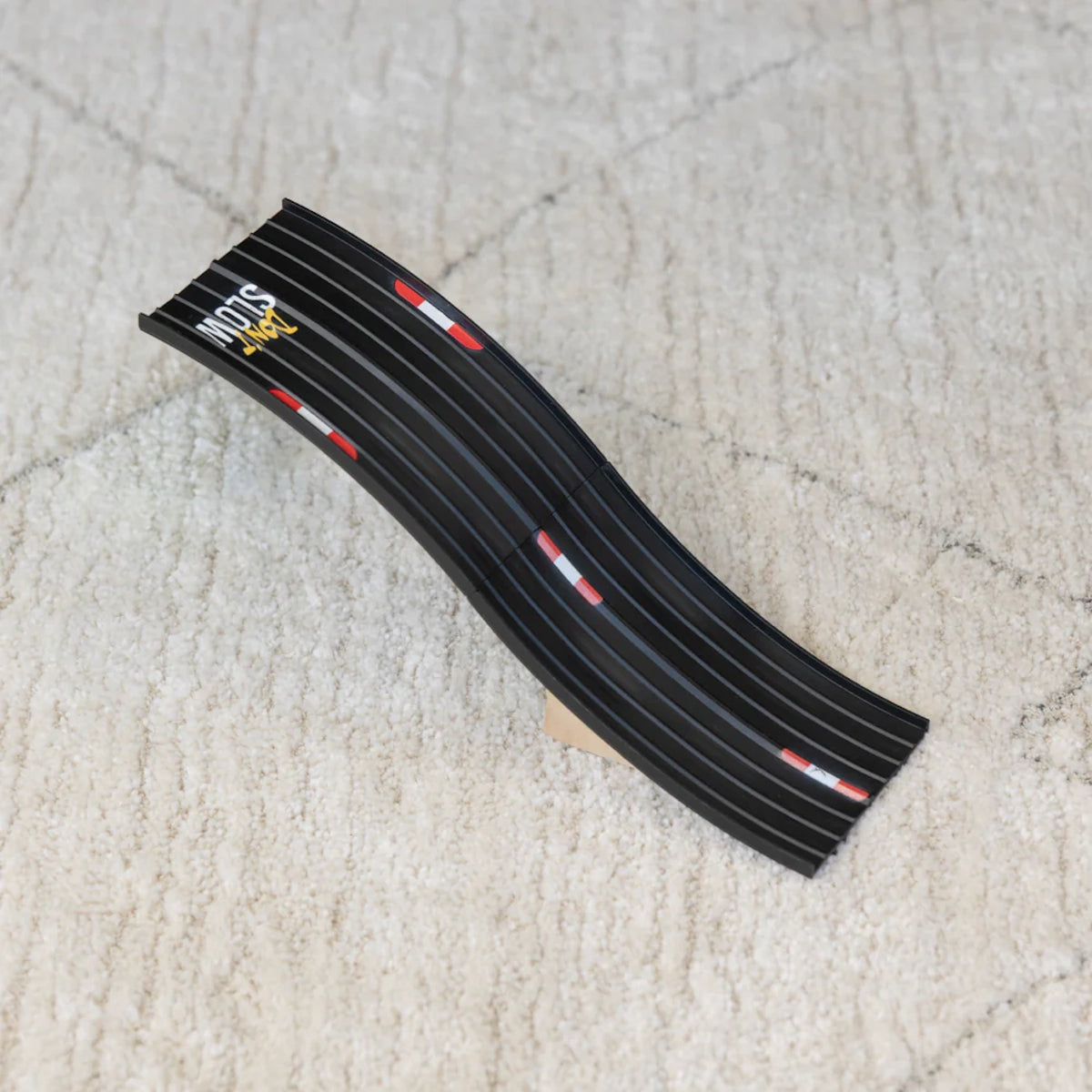 Black Candylab Roadworks Hop Expansion Pack wooden toy ramp with "Don't Slow Down" text on a white textured rug.