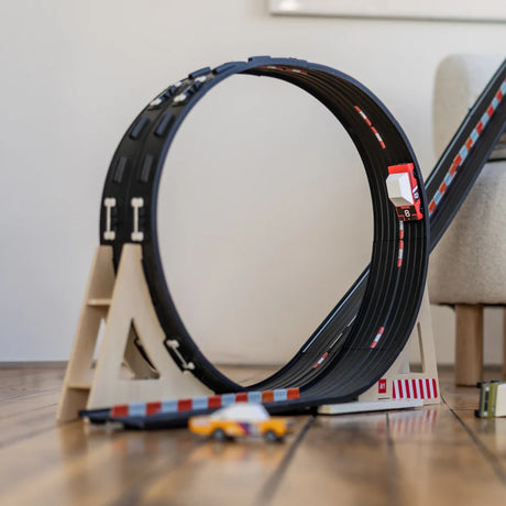 Candylab Roadworks Loop Add-on Kit with wooden toy car racing through a circular track on a light wood floor.