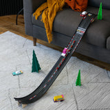 Candylab wooden toy cars racing down a black track ramp leaning on a gray sofa in a modern living room setting.