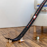 Candylab wooden toy cars racing down a long black rubber Roadworks track ramp on a hardwood floor.