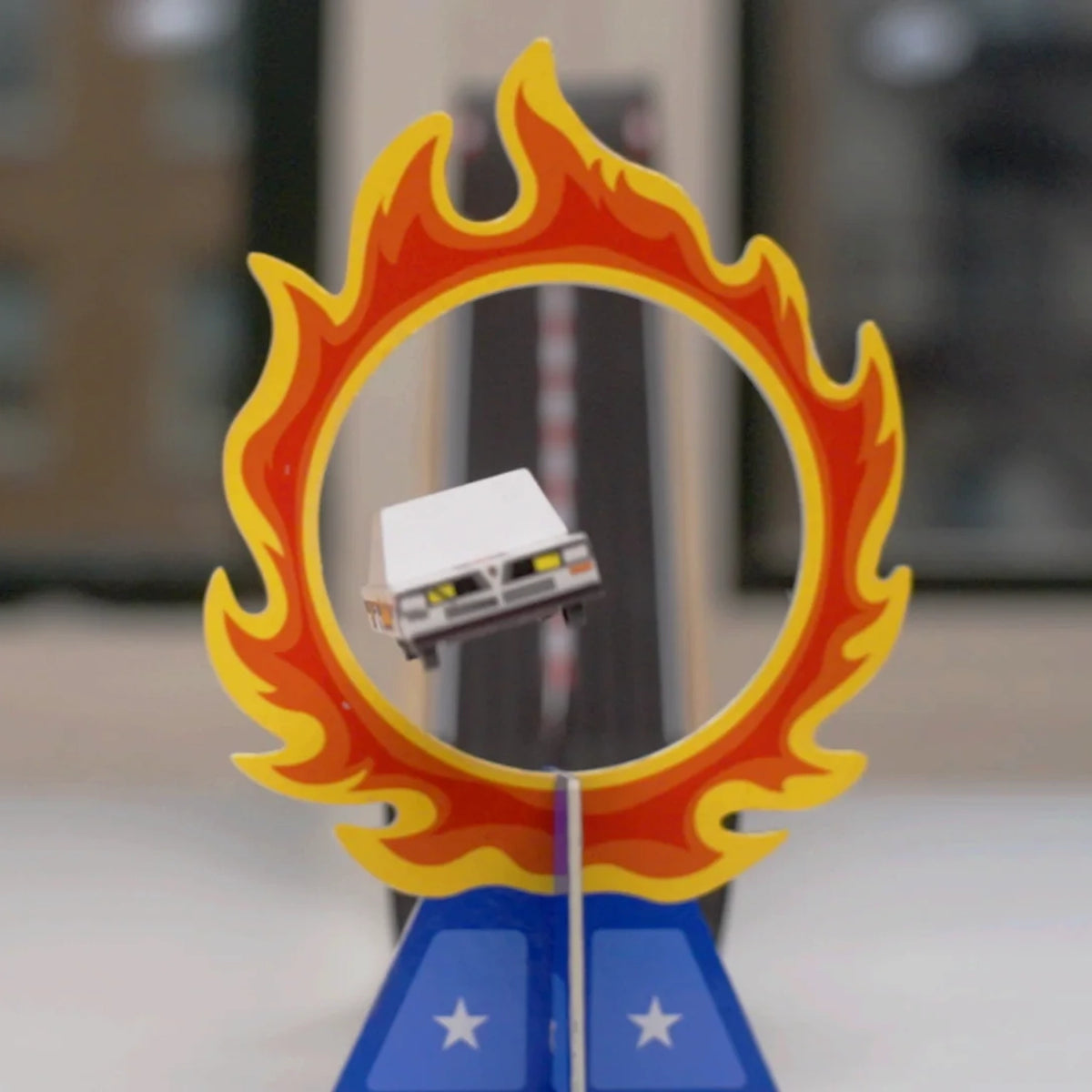 Candylab Roadworks stunt jump playset featuring a white wooden toy car flying through a flaming hoop on a blue star base.