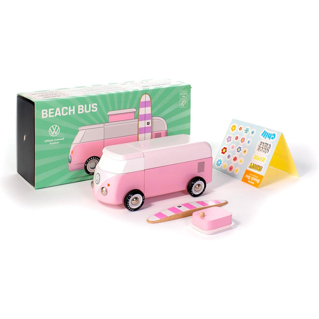 Pink wooden toy VW beach bus with its green packaging box, a toy surfboard, pop-top, and a sticker sheet.