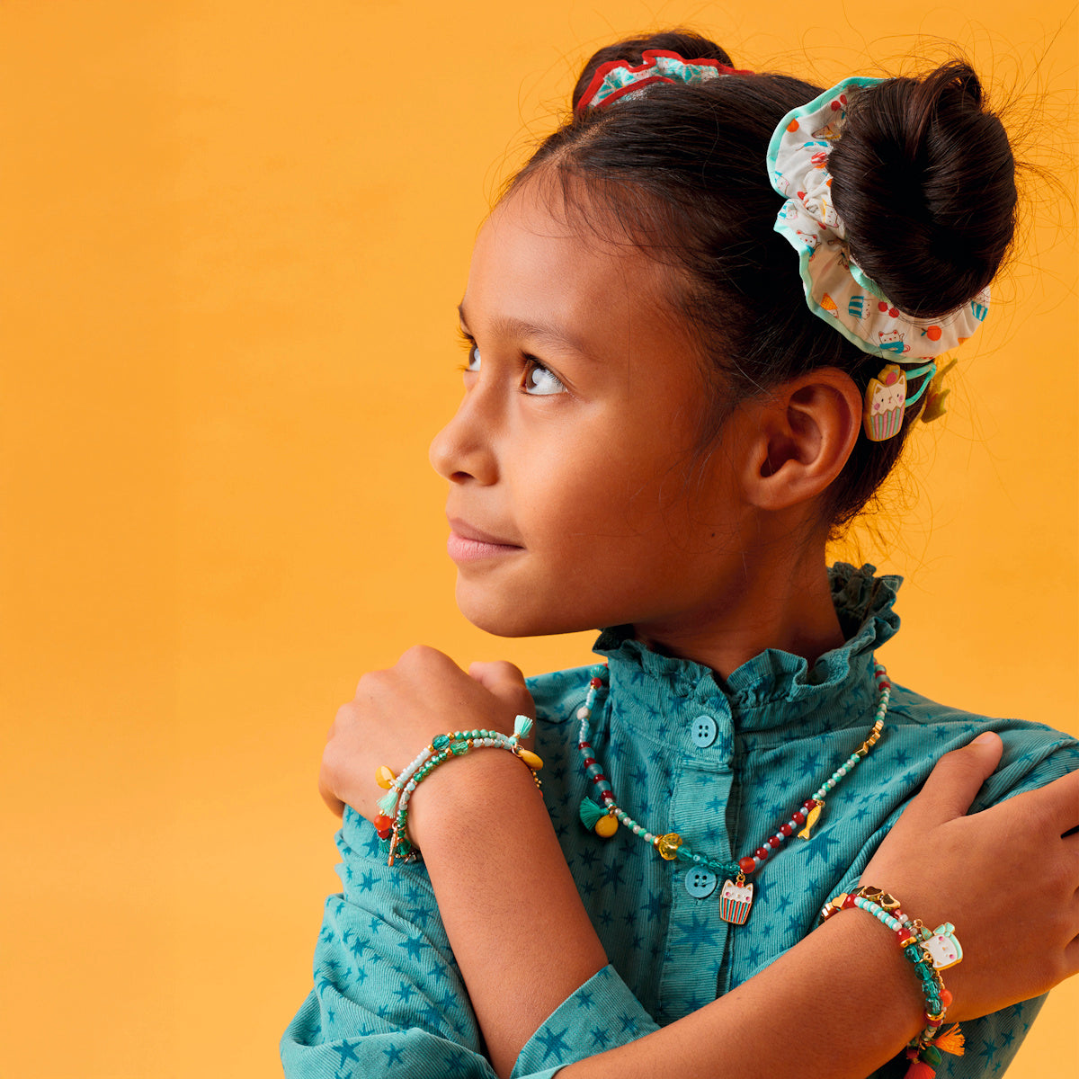 Girl wearing Hanae cat collection stacked bracelets with matching cat charm necklace and Emma scrunchie bun.