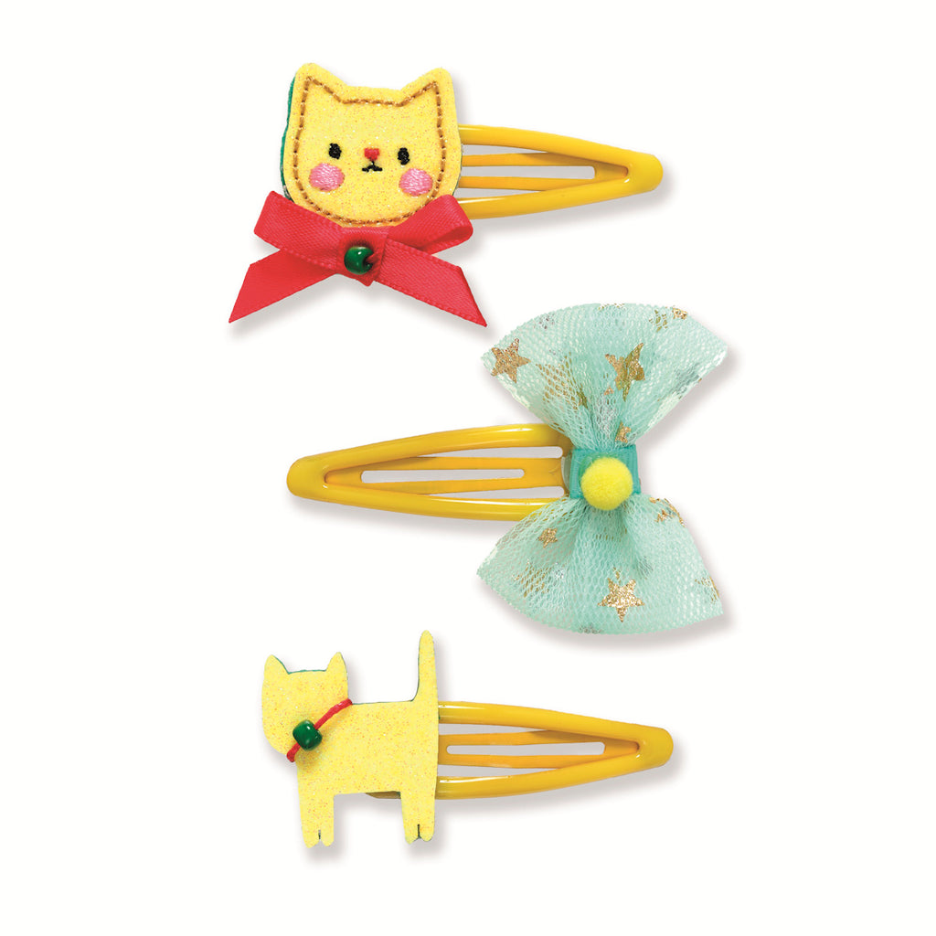 Three cute yellow hair clips: a cat face with a red bow, a teal bow with gold stars, and a cat silhouette. Each clip has cheerful details.