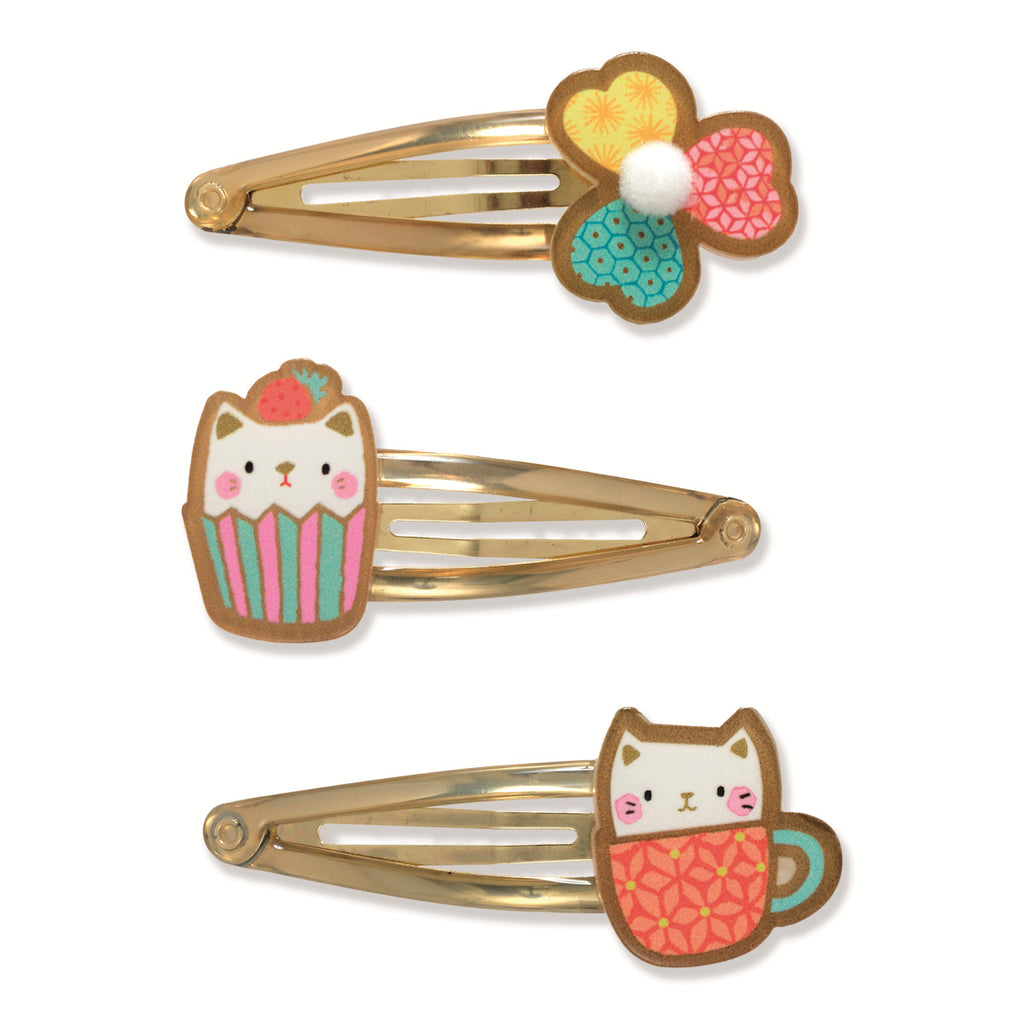 Three playful hair clips on a white background. Each has a cute animal design, a flower, a cupcake cat, and a cat in a mug, all on gold clips.
