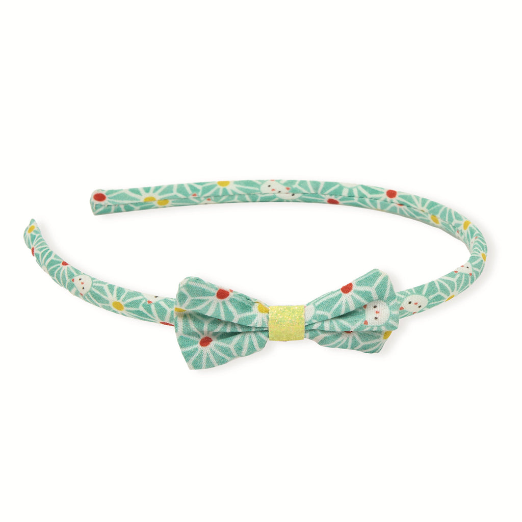 Aquamarine headband with a matching bow, featuring a playful floral pattern in red, yellow, and white. It exudes a cheerful and whimsical vibe.