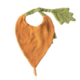 Orange carrot-shaped baby bib with a green leaf strap and fringe tip on a white background.