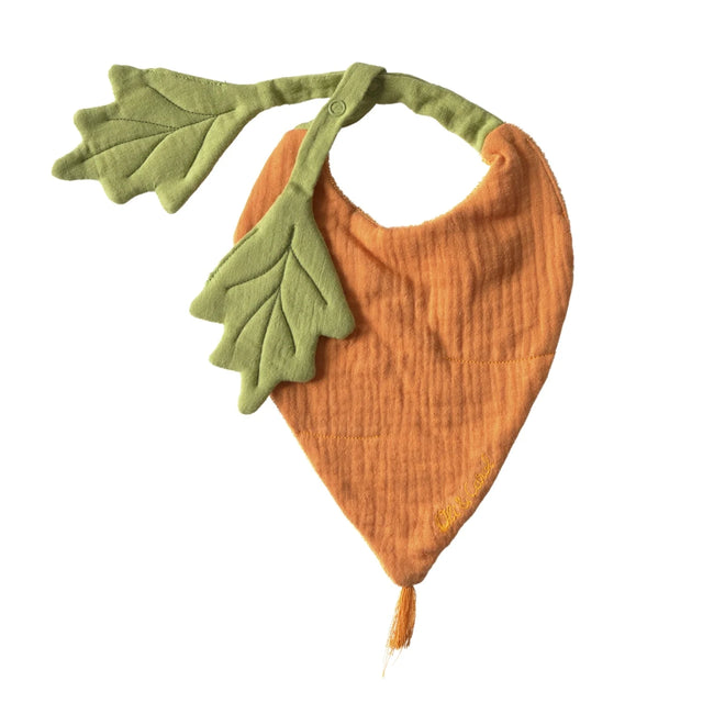 Orange carrot-shaped muslin baby bib with green leaf straps and a small tassel on a plain white background.