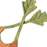 Close-up of a carrot-shaped baby bib with green leaf-shaped straps and snap fasteners on a white background.