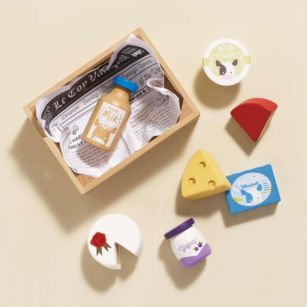 Wooden toy crate containing colorful toy groceries: milk bottle, cheese, yogurt, and cream. Bright, playful, and inviting.