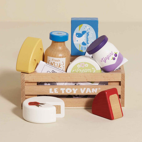 Wooden crate filled with toy dairy products and cheeses on a beige background.