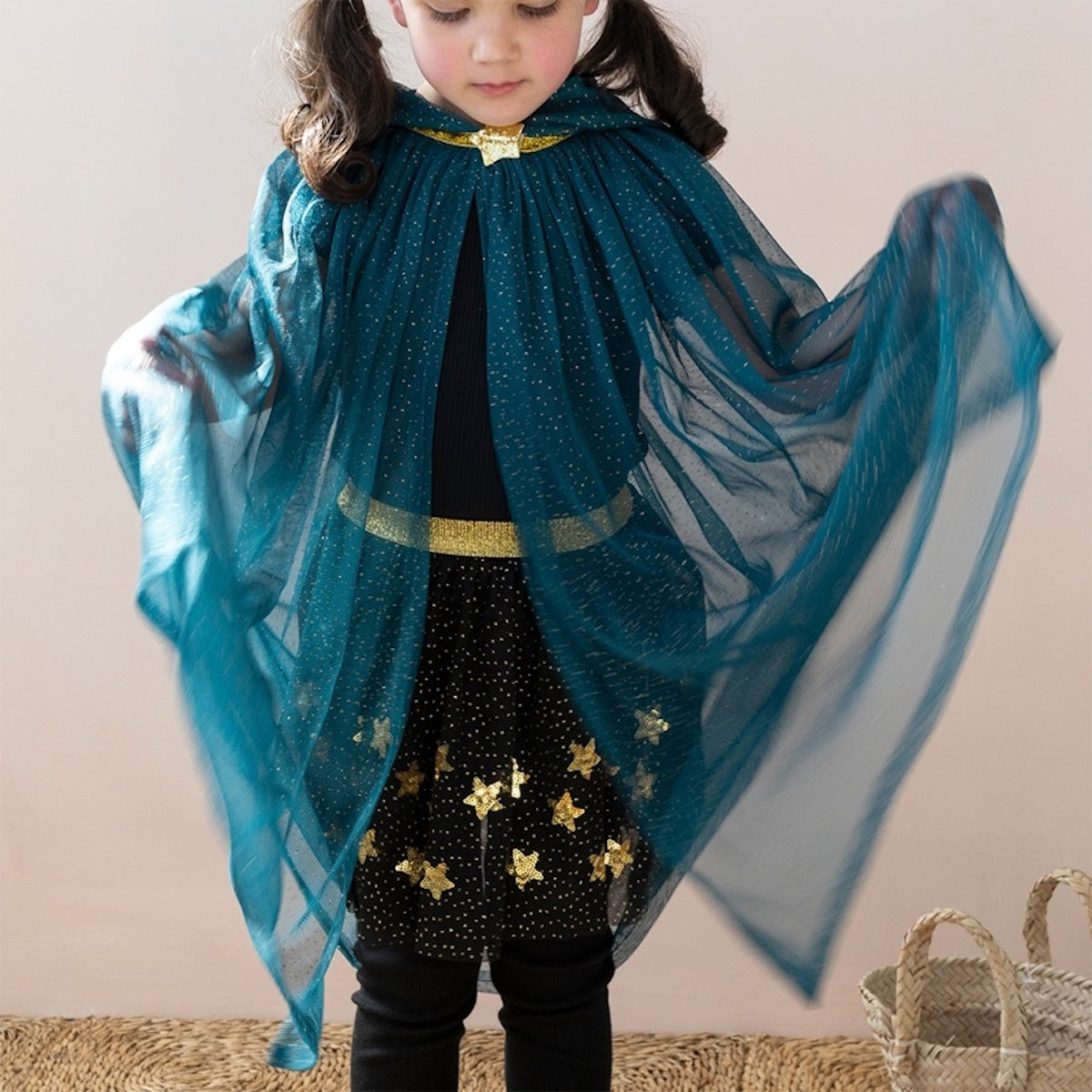 Young girl in a sheer teal glitter cape with gold star accents and a matching star collar clasp.