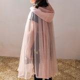 Child wearing a sheer light pink glitter cape with a hood, viewed from the back during dress-up play.