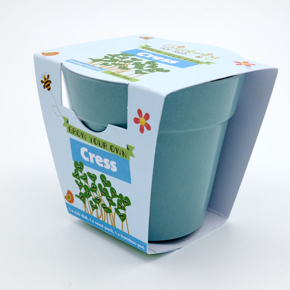 A blue bamboo plant pot packaged in a "Grow Your Own Cress" children's gardening kit cardboard sleeve.