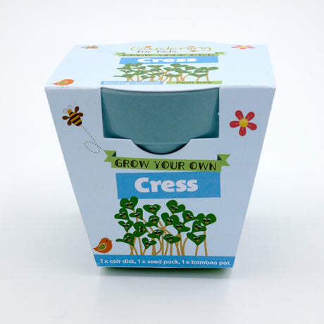 Packaging for a "Grow Your Own Cress" kit, showing a blue bamboo pot and cartoon smiling cress sprouts.