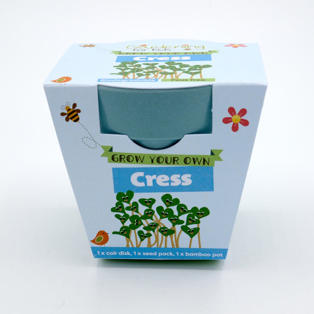 Packaging for a "Grow Your Own Cress" kit, showing a blue bamboo pot and cartoon smiling cress sprouts.