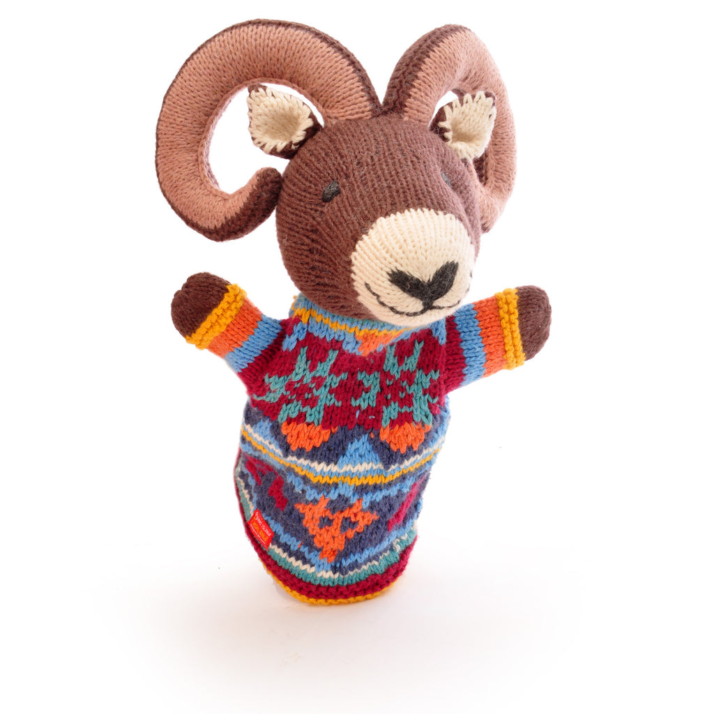 Knitted ram hand puppet with curled horns, wearing a colorful, patterned sweater in blue, red, and orange. The toy has a cheerful expression.