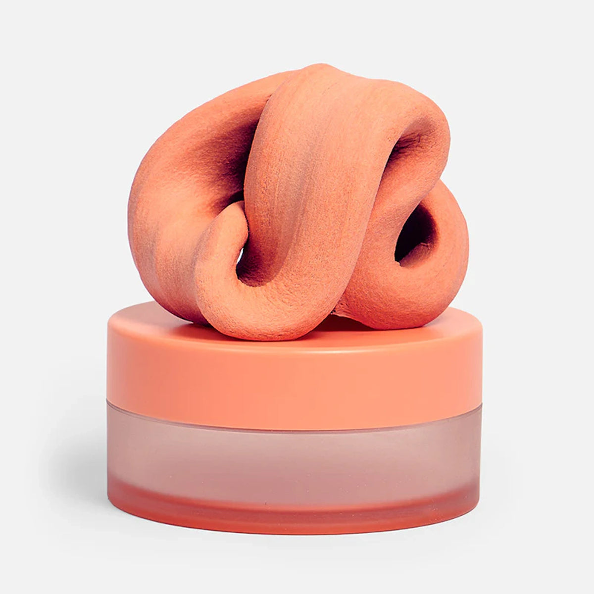 Swirled clementine-orange focus putty resting on top of its matching circular container.