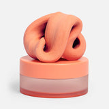 Swirled clementine-orange focus putty resting on top of its matching circular container.