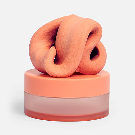 Swirled clementine-orange focus putty resting on top of its matching circular container.