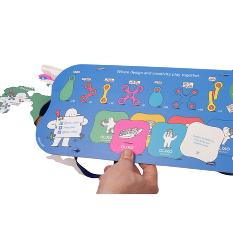 Hand holding a blue Clixo Classroom Pack box showing various magnetic toy shapes, quantities, and colorful cards.