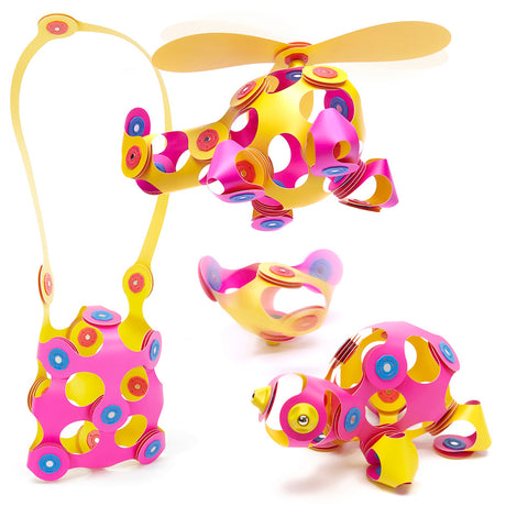 Pink and yellow magnetic toy creations including a helicopter, handbag, turtle, and top against a white backdrop.