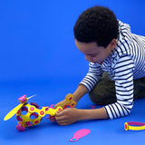A young boy plays with a magnetic toy helicopter against a bright blue background.