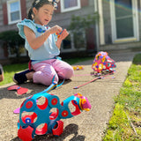 Young girl sitting outside on a walkway playing with colorful flexible magnetic toy pieces and creations.