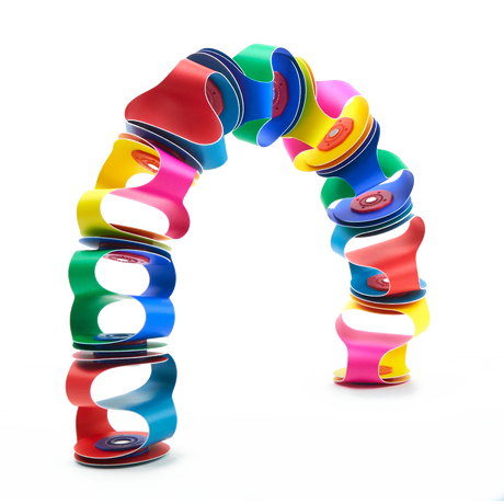 Colorful flexible magnetic toy pieces connected to form a vibrant, freestanding arch against a white backdrop.