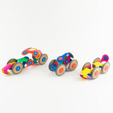 Three colorful toy cars built with flexible magnetic pieces and wooden wheels on a plain white background.
