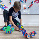 Boy playing on floor with colorful magnetic toy vehicles made with the Clixo Wheel Creator Pack.