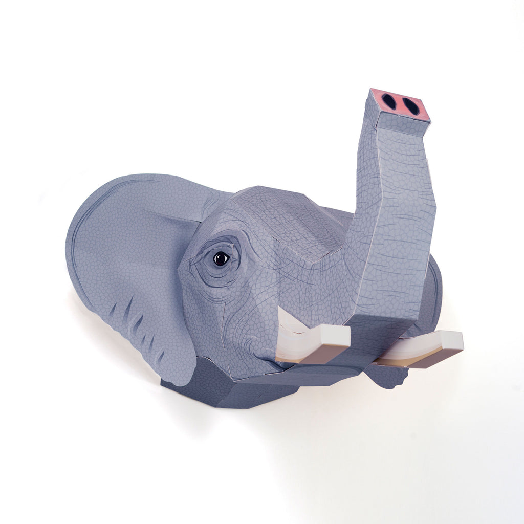 A paper sculpture of an elephant's head with a raised trunk, featuring geometric patterns and textures, set against a plain white background.