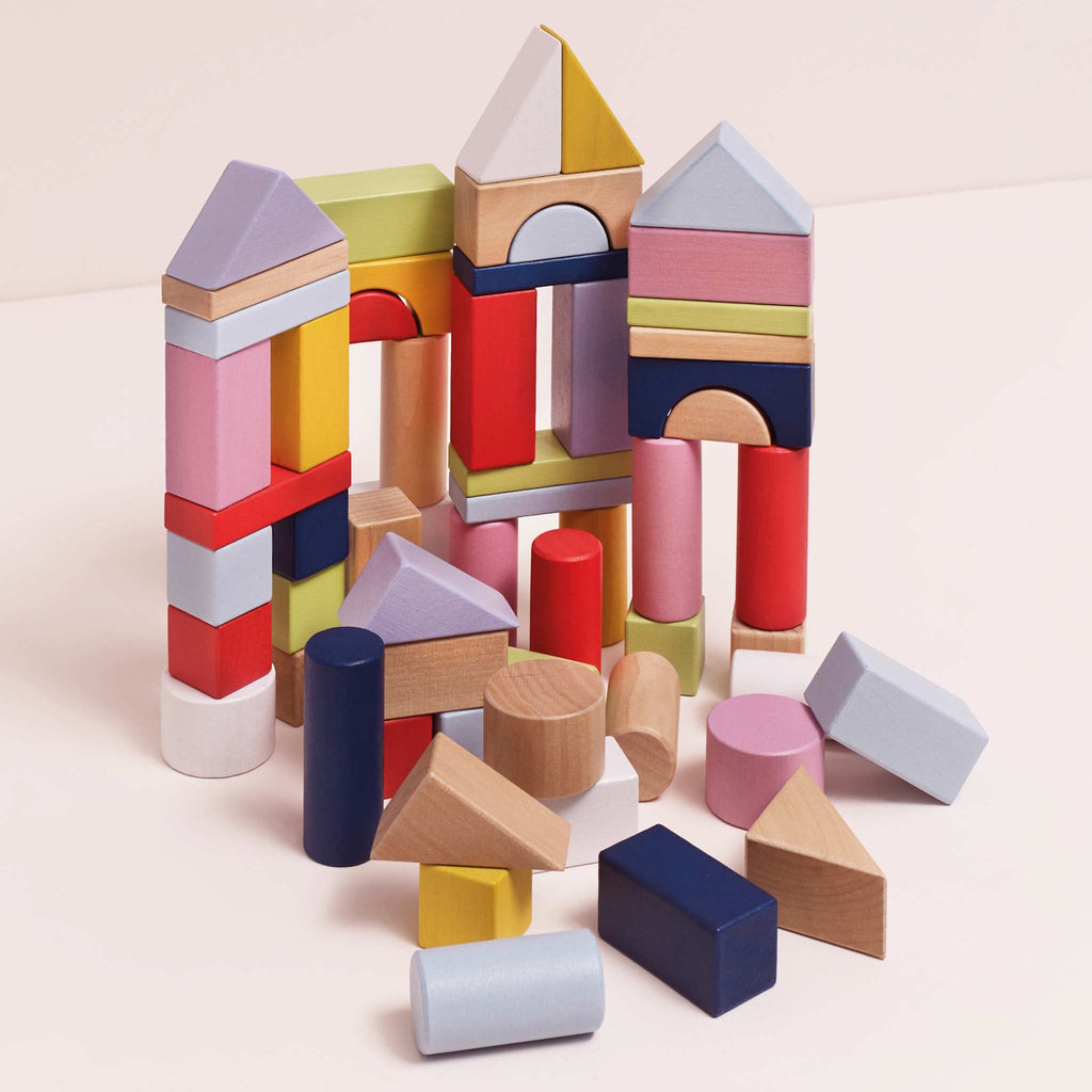 Colorful wooden blocks arranged in a playful structure on a pale surface. Blocks are cylindrical, triangular, and rectangular, conveying creativity and fun.